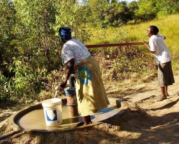 woman in rural countryside carrying water bucket